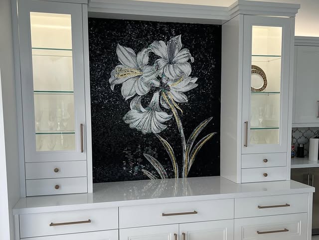 Marble mosaic mural of white lilies on a black ground, set between glass-front cabinets