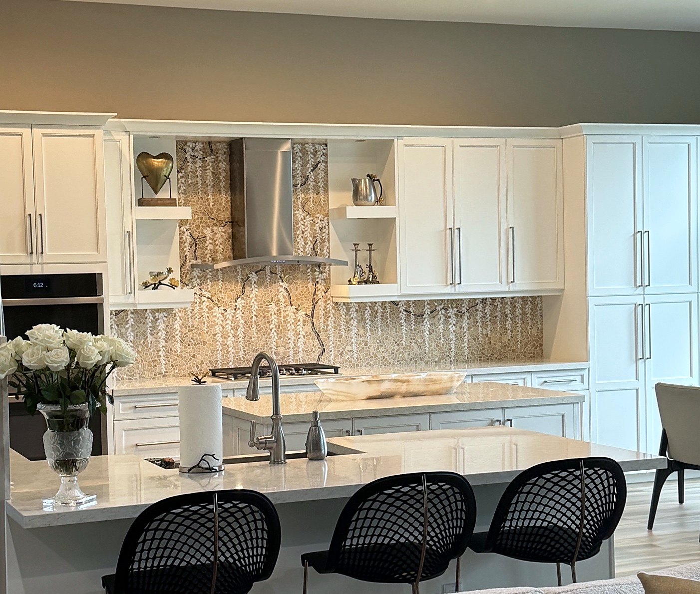 White kitchen with a marble mosaic wisteria backsplash: dark branches and white blossoms hanging down the wall behind the range